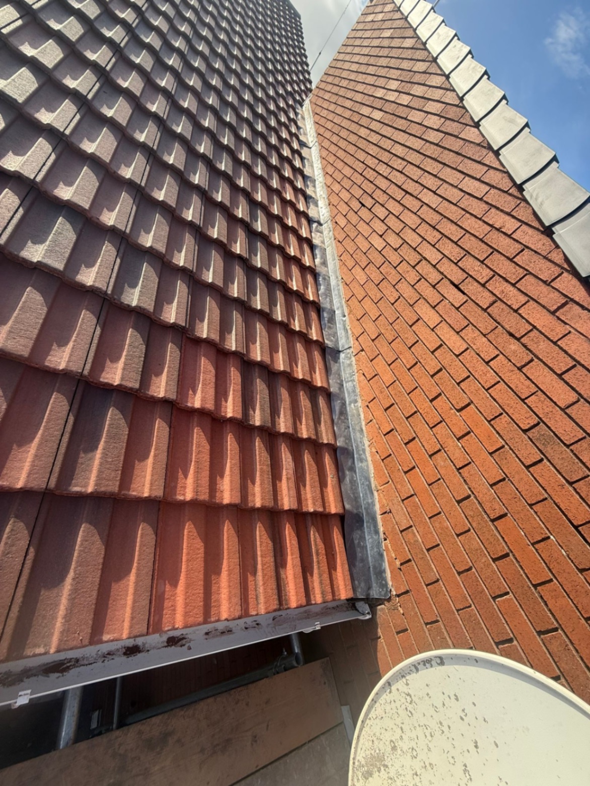 Close-up of new tiled roof and lead flashing alongside chimney stack